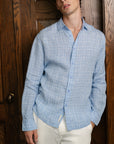 Man wearing a blue checkered shirt against a wooden door background