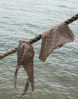 Two checkered bags hanging on a rope over water