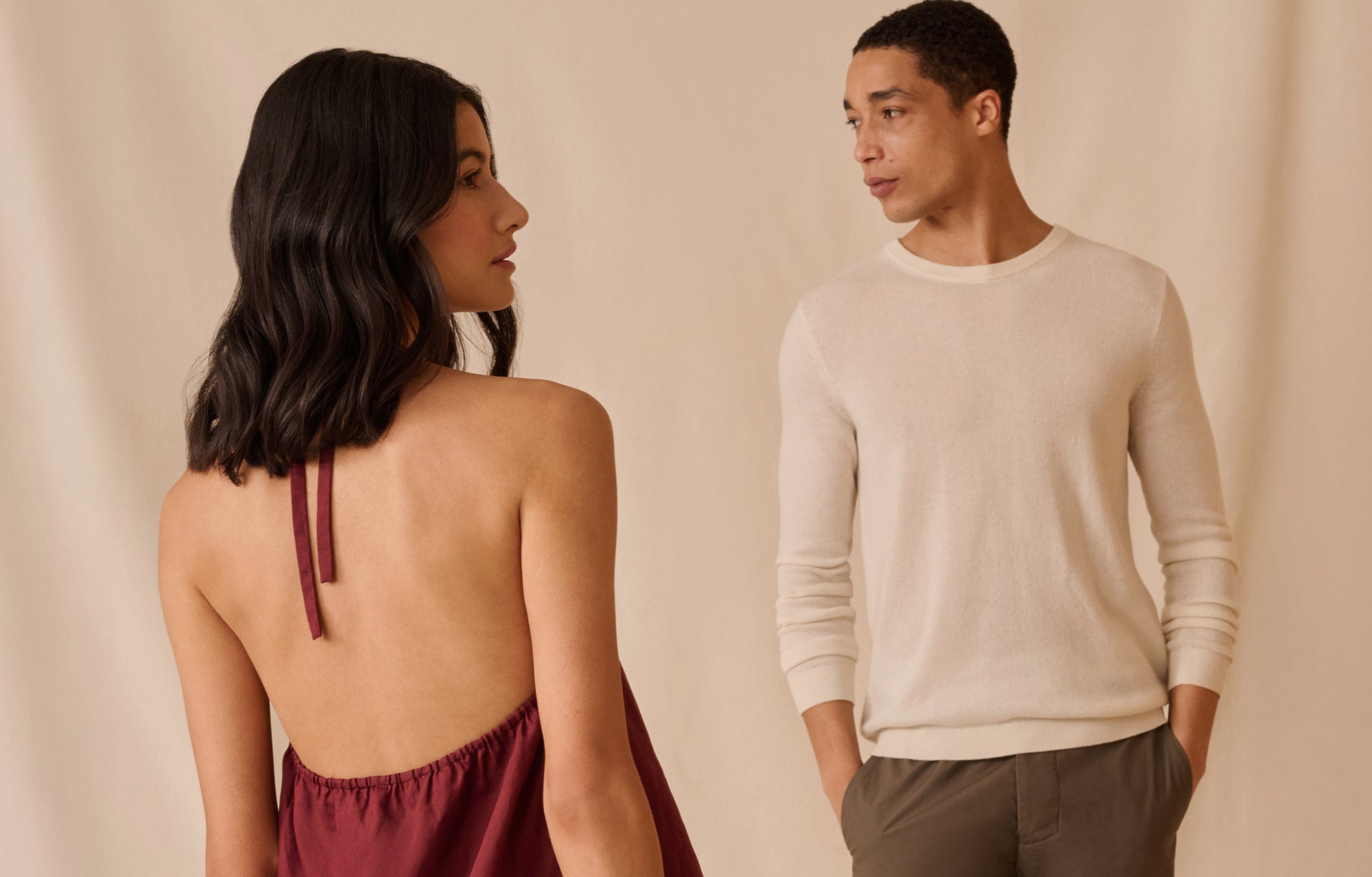 Two people standing facing each other against a beige background