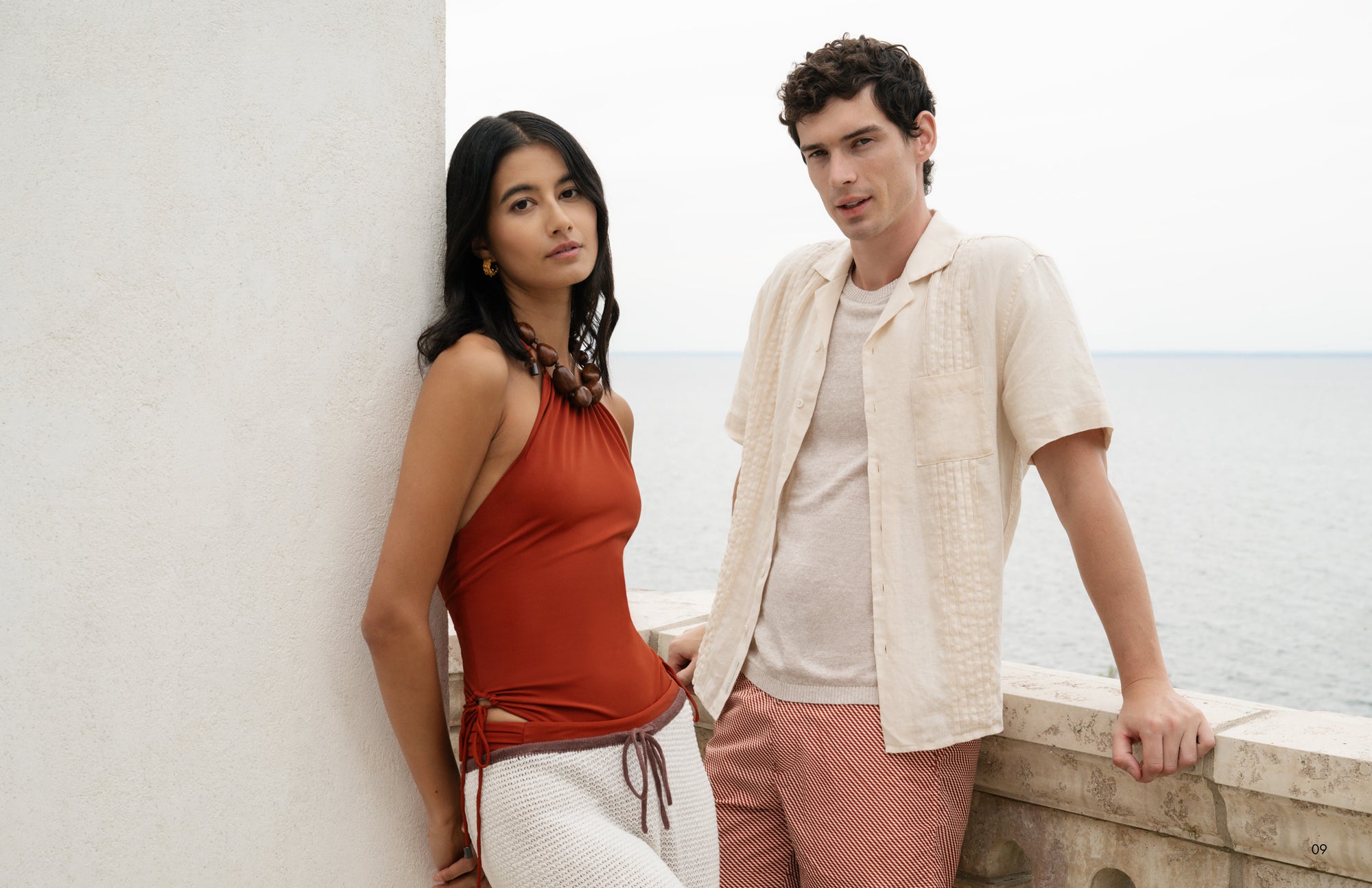 Two people standing by a wall with a light background