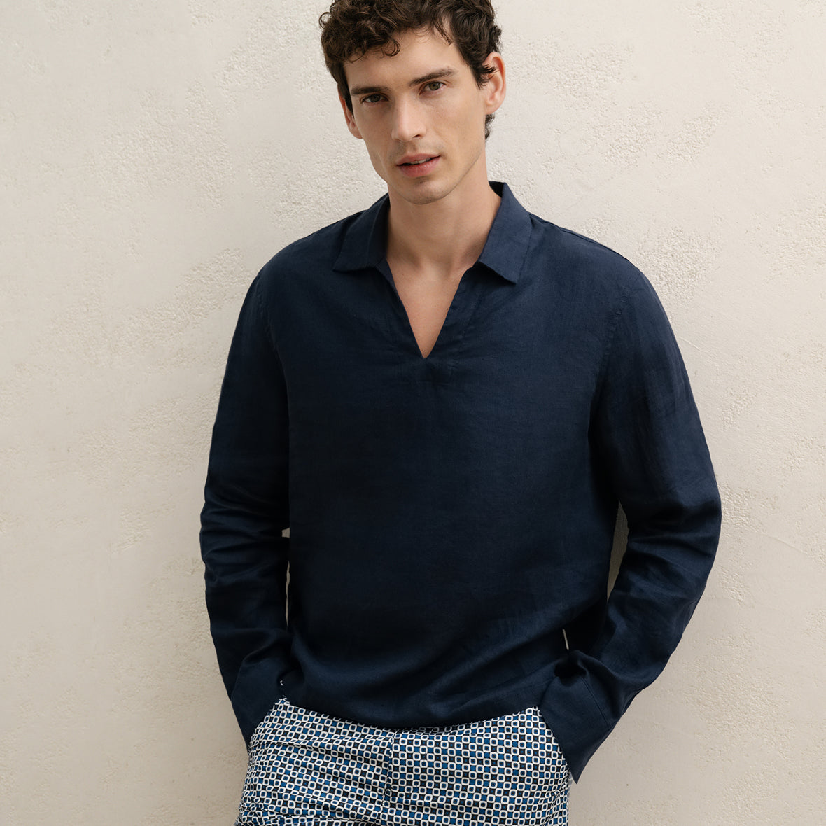 Man wearing a navy long-sleeve shirt against a beige wall