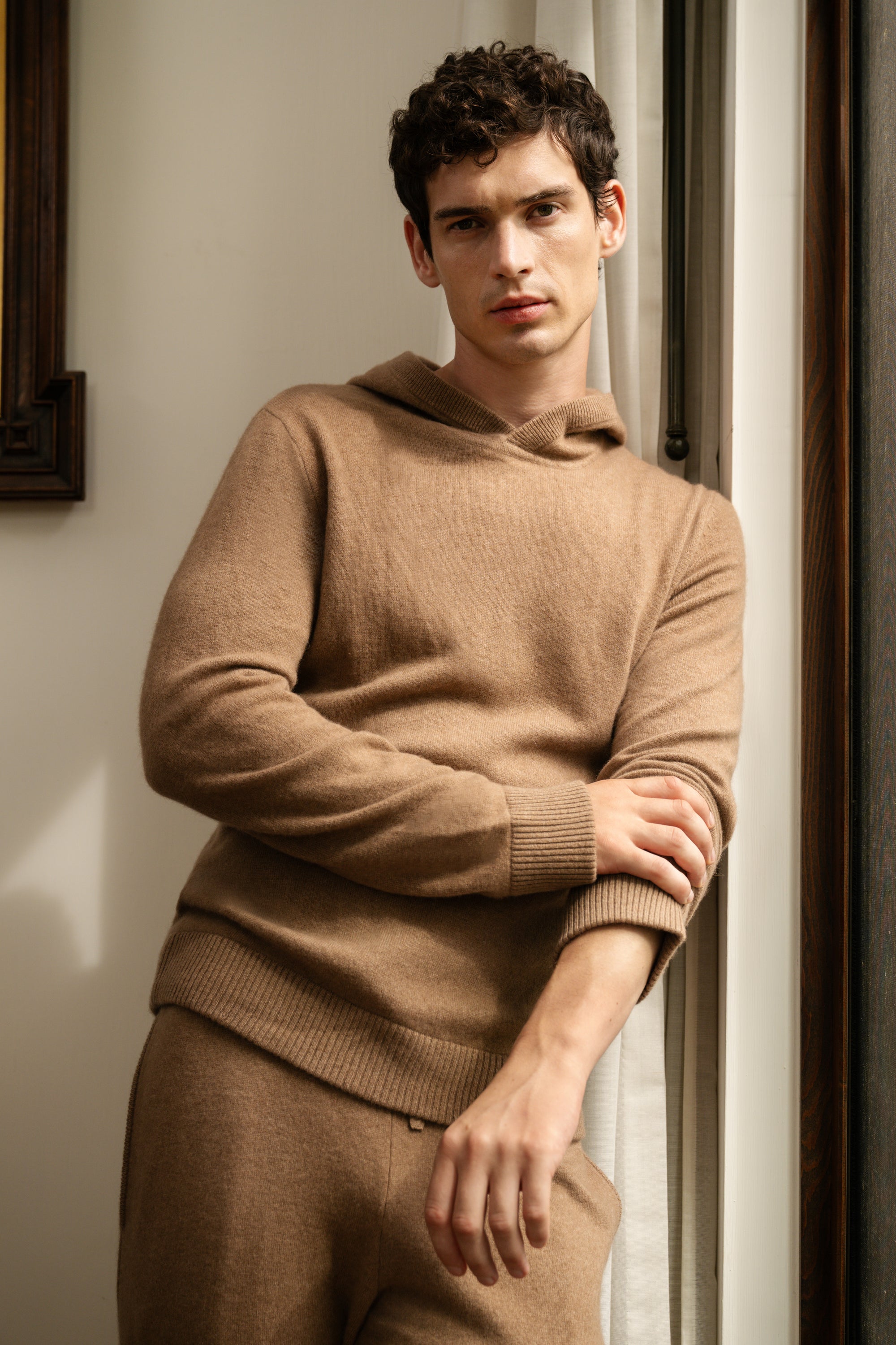 Onia Resort 2026 showing a man standing at the window in a light brown cashmere matching set