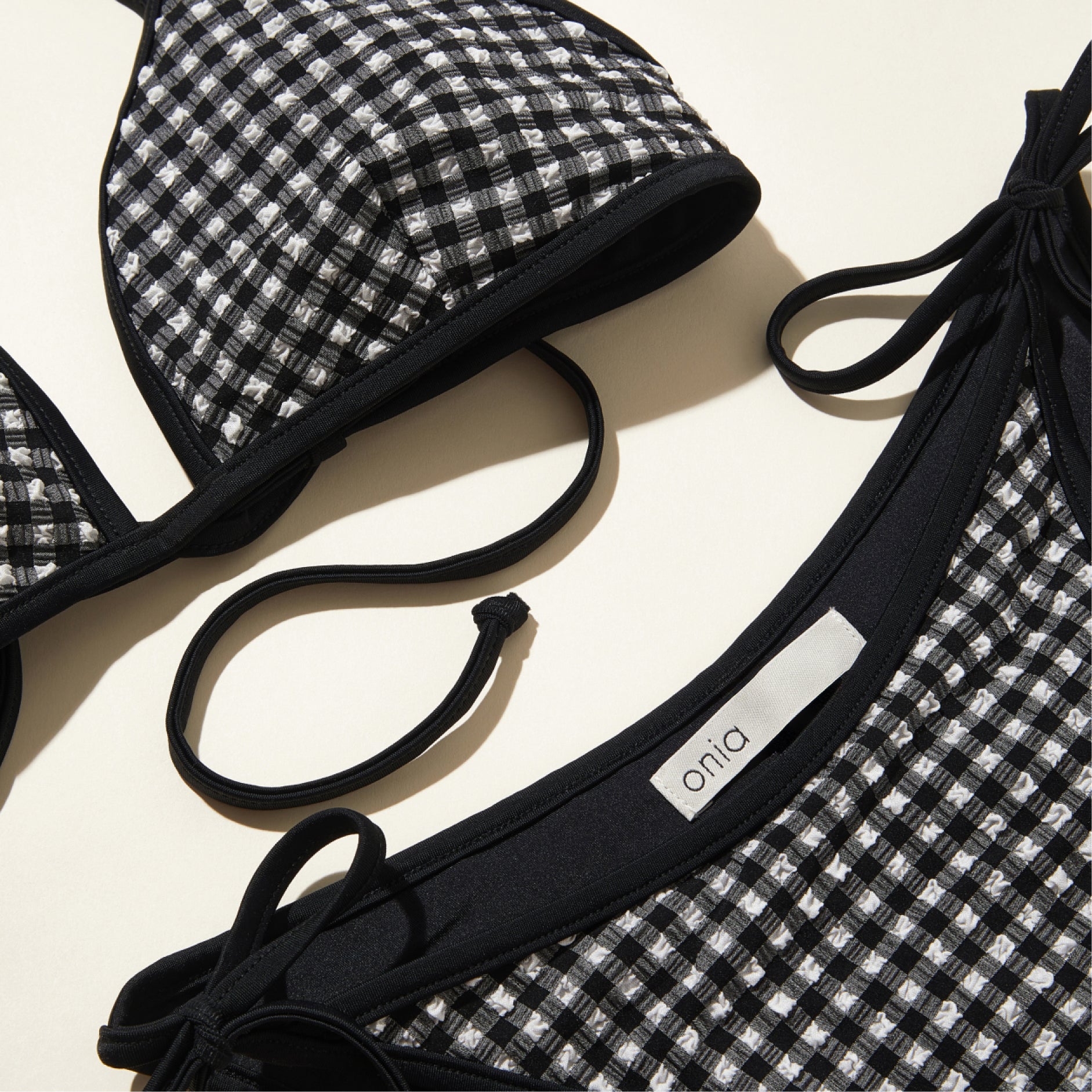 Black and white checkered bikini set with 'onia' label on a beige background