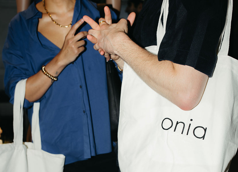 Two people holding hands with 'onia' bags in the foreground