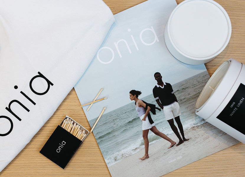 Onia catalog with a couple on a beach, matches, and a candle on a wooden surface.