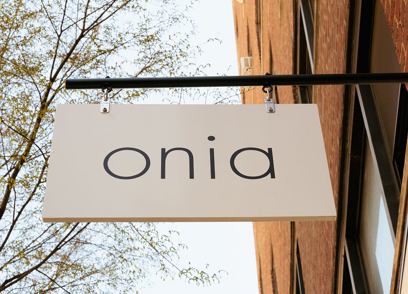 Onia sign hanging outside a building with trees in the background