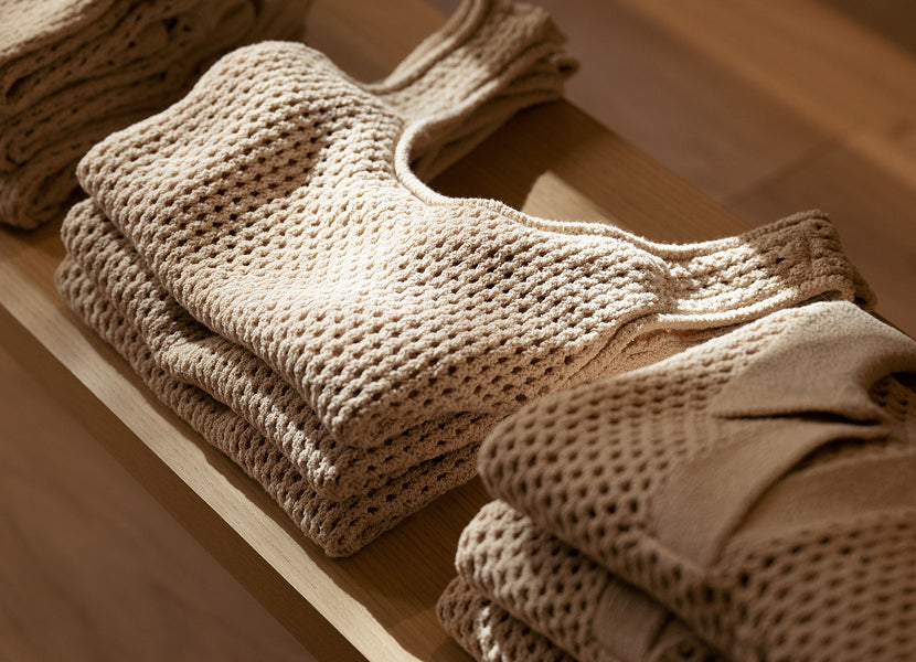 Stack of beige knitted garments on a wooden surface in Onia store